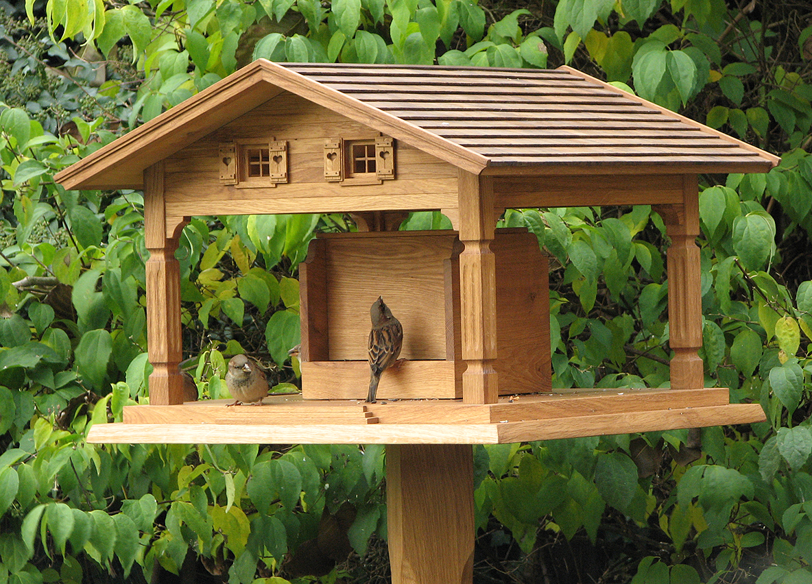 Klassisches Vogelhaus aus Eiche mit offenem Futterplatz und Sperlingen