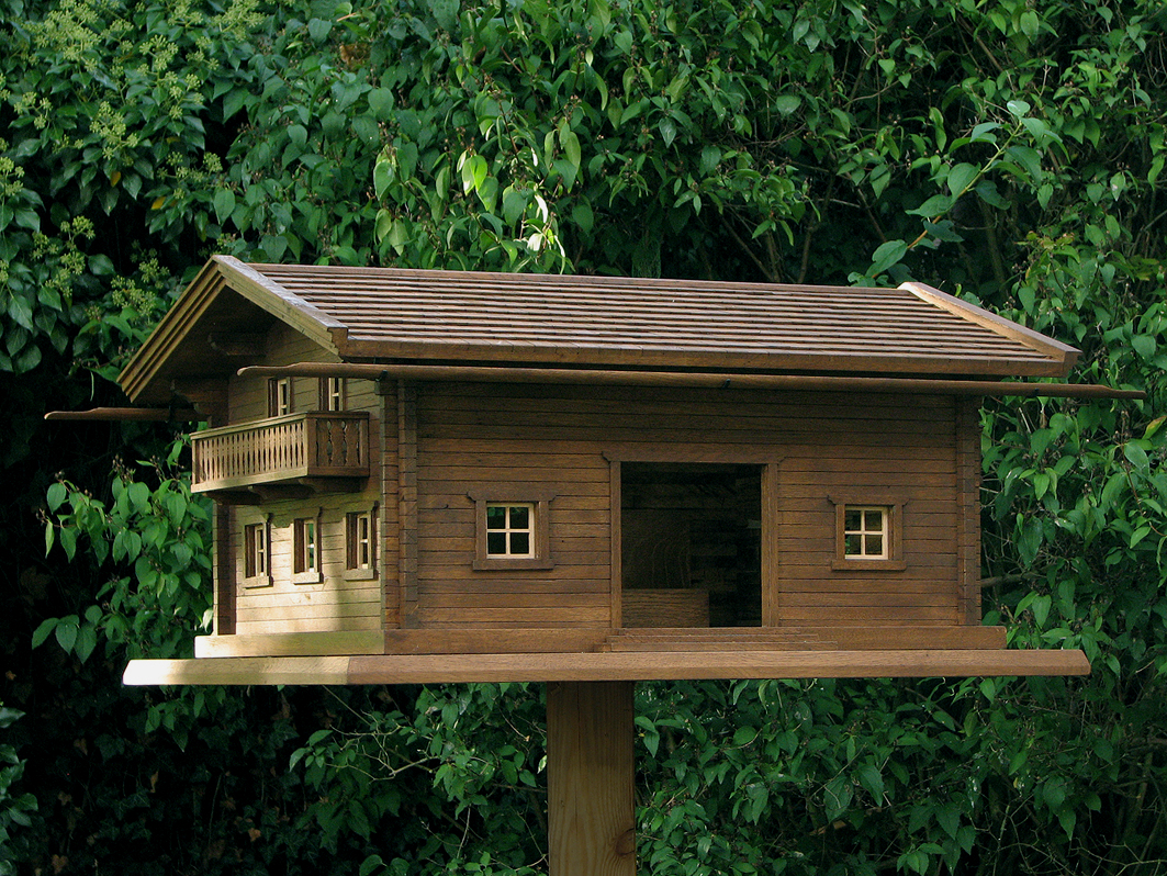 Große Vogelvilla im Chalet-Stil aus Massivholz auf einem Standfuß im Garten